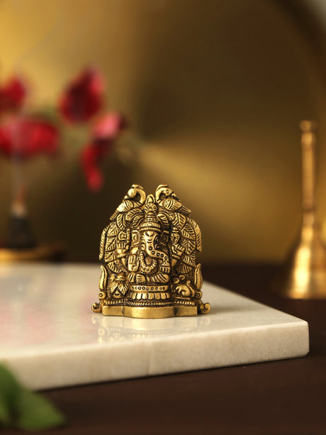 Antique gold brass Ganesha statue with peacock design.