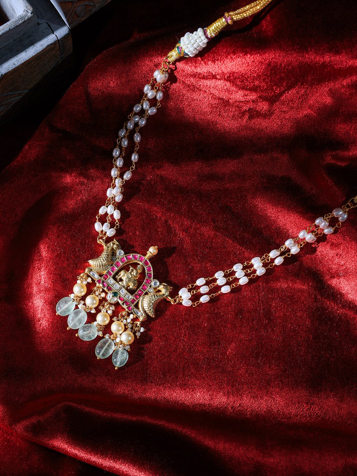 Delicate necklace with pearls and gold elements on a red fabric background