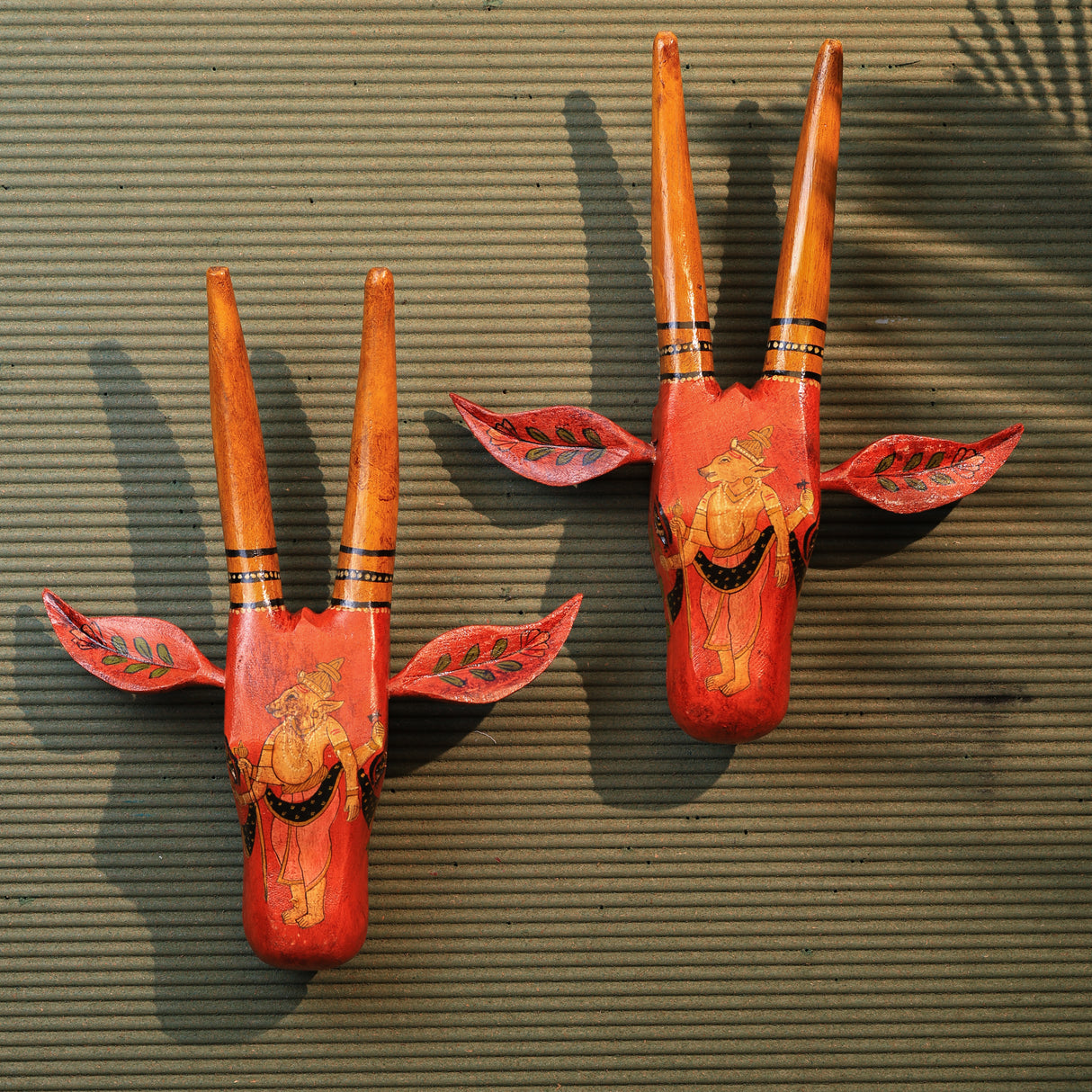 Two hand-painted vintage-style cow face decorations in orange and yellow, mounted on a wall.
