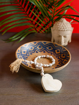 White wooden bead decor string styled in decorative bowl.