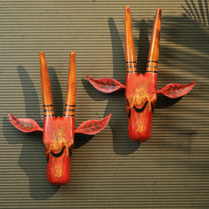 Two hand-painted vintage-style cow face decorations in orange and yellow, mounted on a wall.